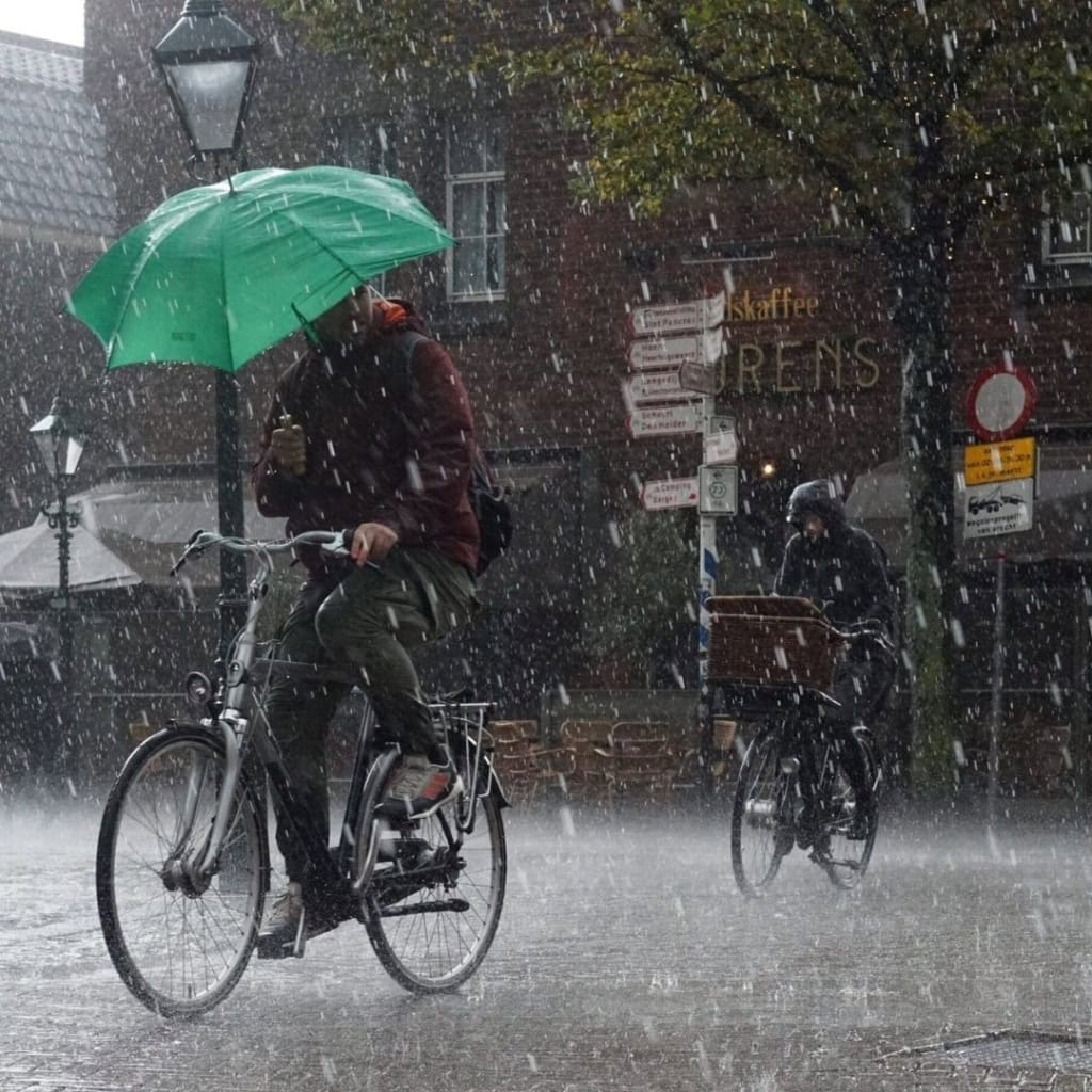 Een foto van mensen die fietsen door hevige neerslag